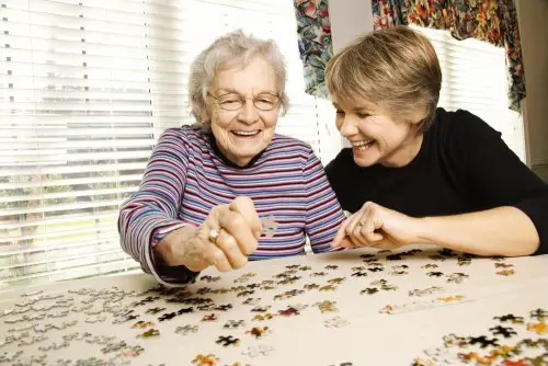 Grandparent and Younger Woman Doing Puzzle